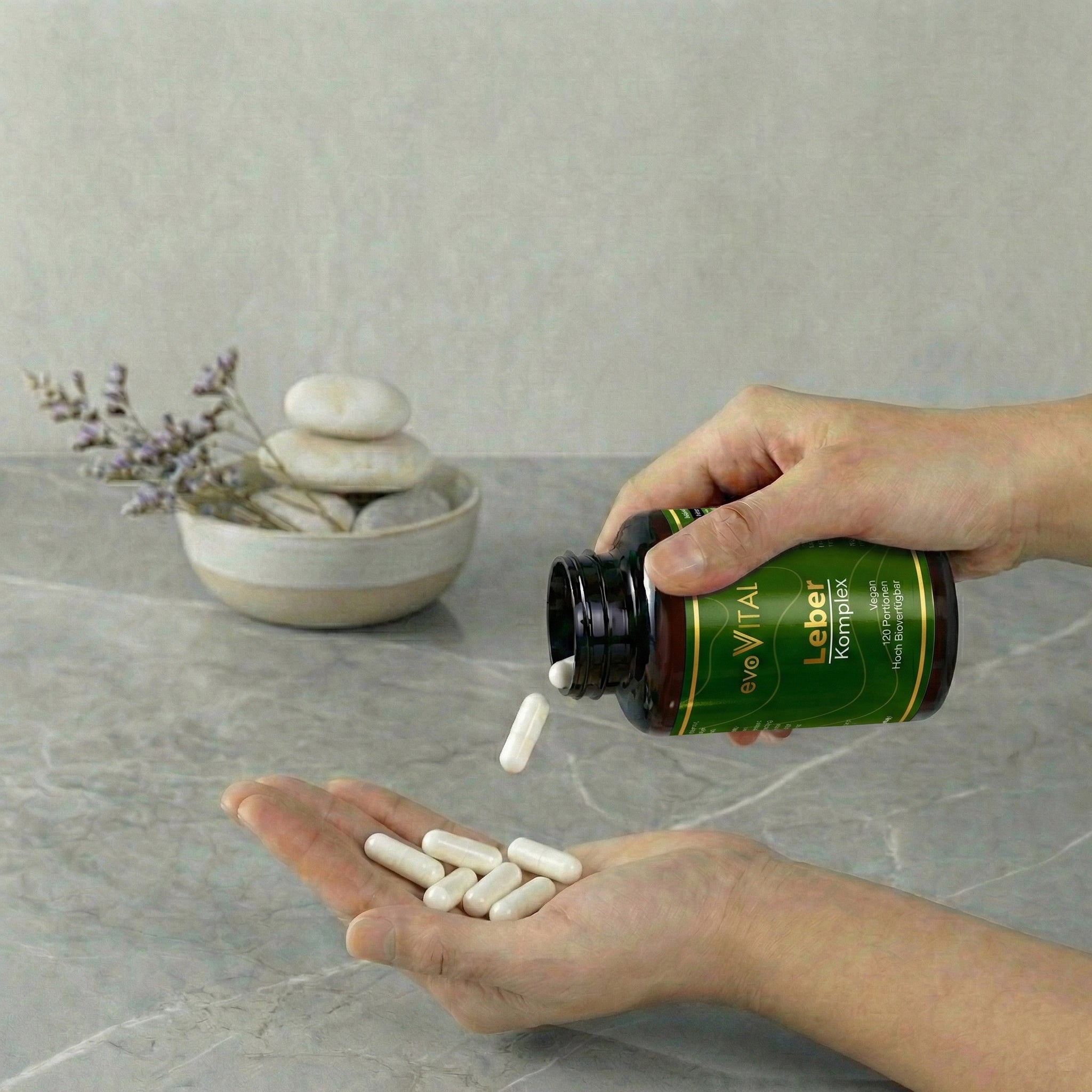 Lifestyle-Aufnahme: Eine Hand präsentiert die Braunglasflasche und die veganen Leber-Komplex-Kapseln als tägliches pflanzliches Supplement.